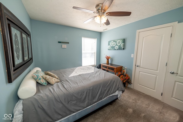 bedroom featuring ceiling fan, a textured ceiling, and dark colored carpet