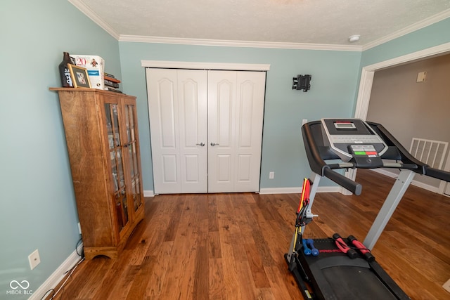 workout area with hardwood / wood-style flooring and crown molding