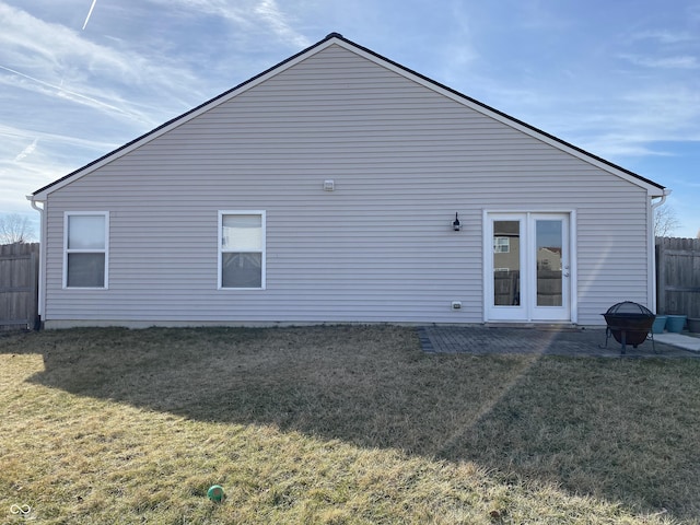 back of property with a yard and an outdoor fire pit