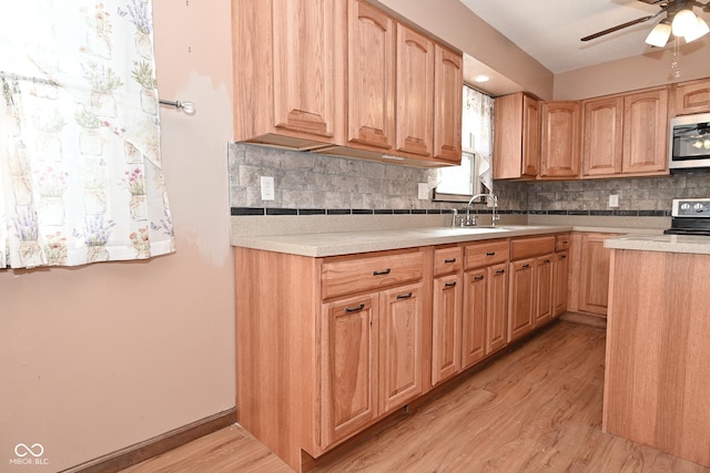 kitchen featuring light brown cabinetry, backsplash, ceiling fan, stainless steel appliances, and light wood-type flooring