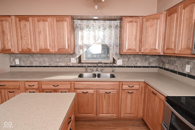 kitchen with a sink, decorative backsplash, light wood-style flooring, and light countertops