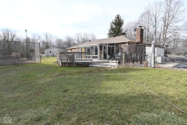 rear view of house featuring a wooden deck, a yard, and a sunroom