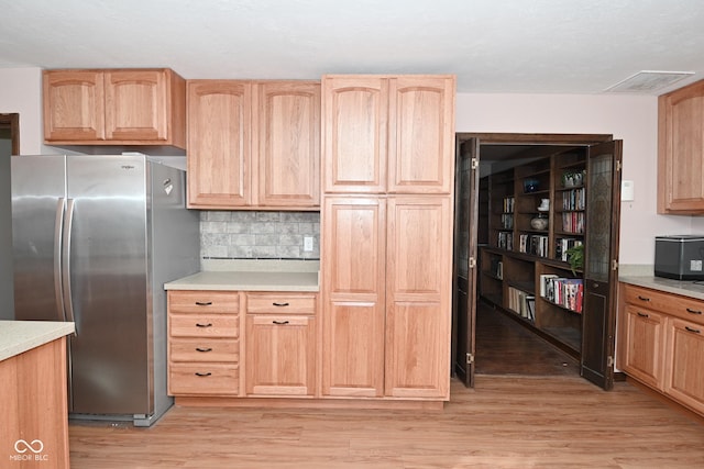 kitchen featuring light wood-type flooring, stainless steel fridge, tasteful backsplash, and light brown cabinets