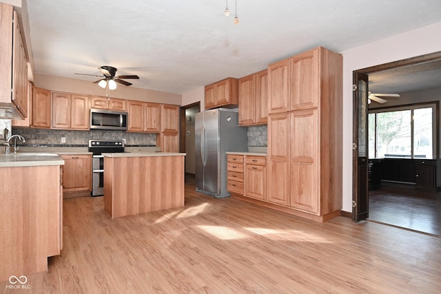 kitchen featuring light wood-style floors, appliances with stainless steel finishes, a ceiling fan, and light countertops