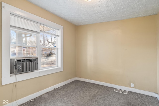 carpeted spare room featuring cooling unit and a textured ceiling