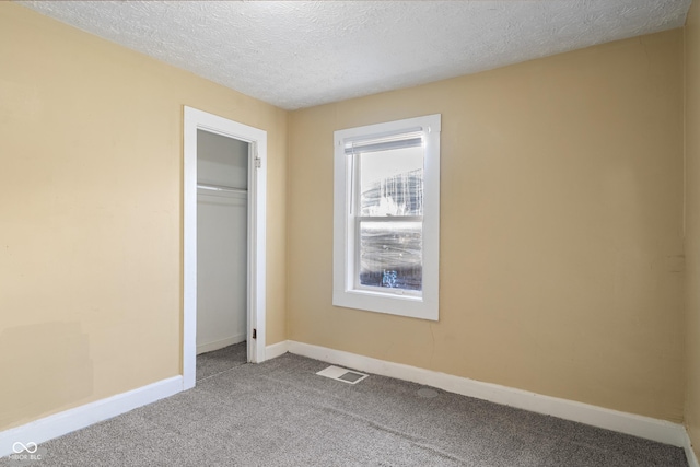 unfurnished bedroom featuring a closet, light carpet, and a textured ceiling