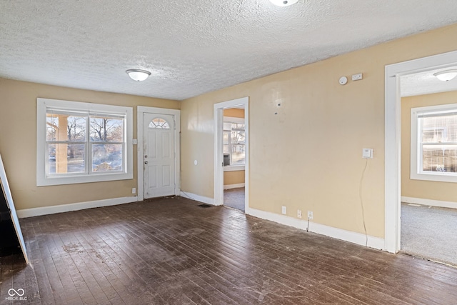 foyer entrance with dark hardwood / wood-style floors and a textured ceiling