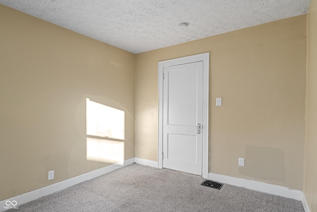 carpeted empty room featuring a textured ceiling