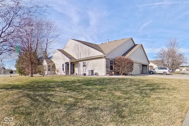 exterior space featuring a garage, cooling unit, and a lawn