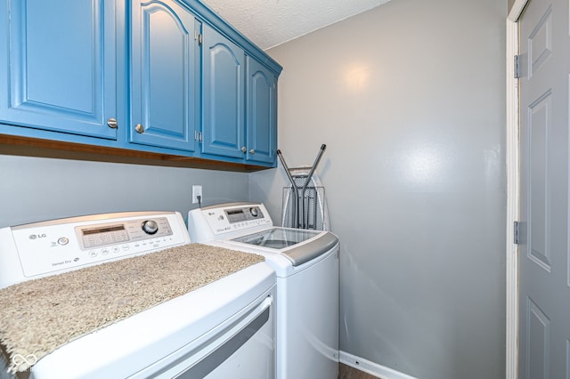 clothes washing area with washing machine and dryer, cabinets, and a textured ceiling