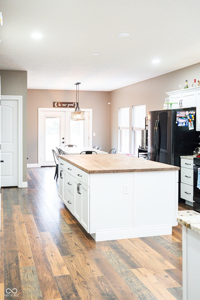 kitchen with stainless steel electric stove, dark hardwood / wood-style floors, decorative light fixtures, white cabinetry, and a center island with sink