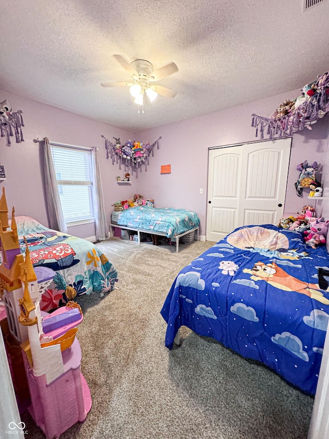 carpeted bedroom with ceiling fan, a closet, and a textured ceiling