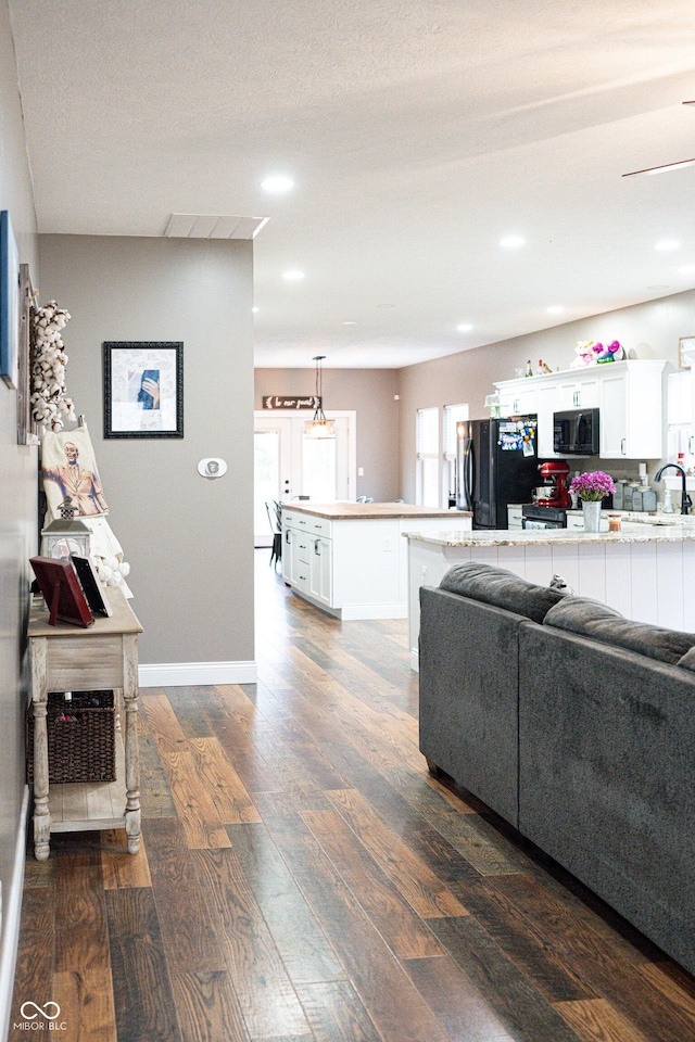 living room featuring sink, dark wood-type flooring, and a textured ceiling