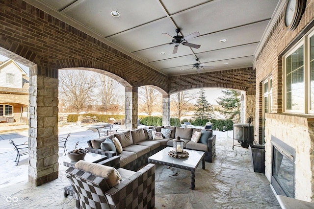 view of patio / terrace with ceiling fan and an outdoor living space with a fireplace