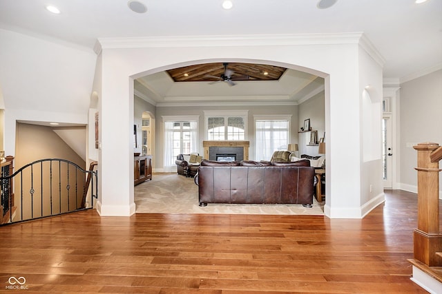 living room featuring hardwood / wood-style flooring, ornamental molding, a raised ceiling, and ceiling fan