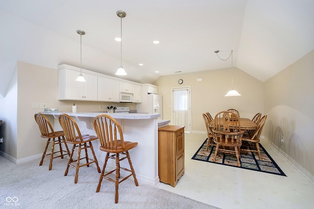 kitchen with hanging light fixtures, white cabinetry, white appliances, and kitchen peninsula