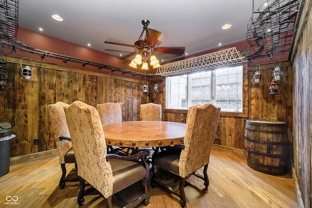 dining area featuring ceiling fan, light hardwood / wood-style flooring, and wood walls