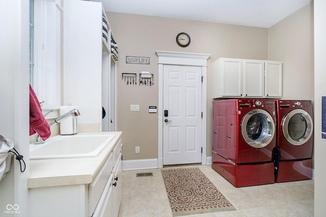 clothes washing area featuring cabinets, sink, washing machine and dryer, and light tile patterned floors