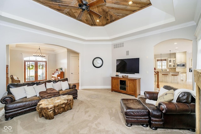 carpeted living room with ornamental molding, a tray ceiling, and a wealth of natural light