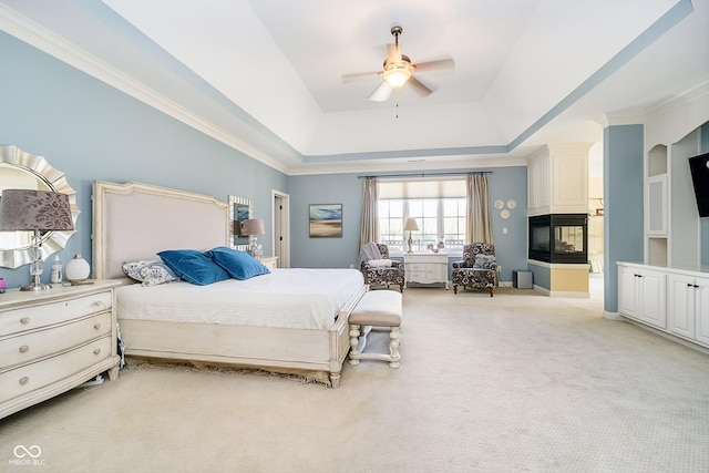 carpeted bedroom with crown molding, a tray ceiling, ceiling fan, and a multi sided fireplace