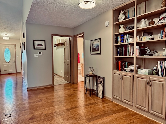 hallway featuring wood-type flooring and a textured ceiling