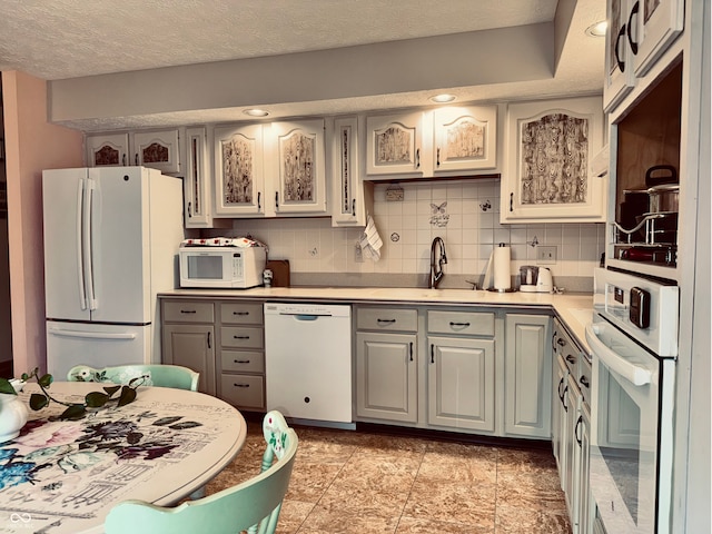 kitchen with gray cabinets, sink, white appliances, and decorative backsplash