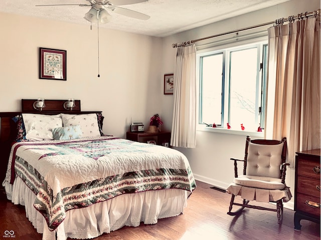 bedroom featuring ceiling fan, wood-type flooring, and a textured ceiling