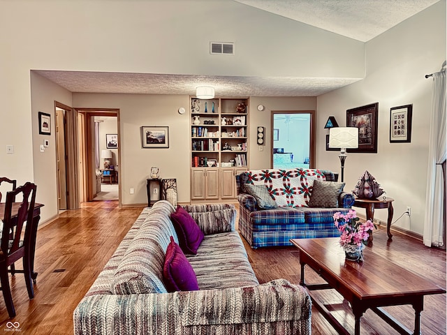 living room featuring lofted ceiling, hardwood / wood-style floors, and a textured ceiling