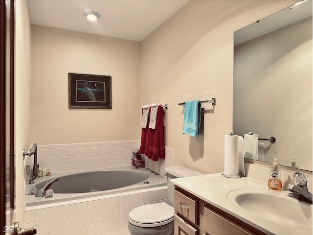 bathroom with tiled tub, vanity, and toilet