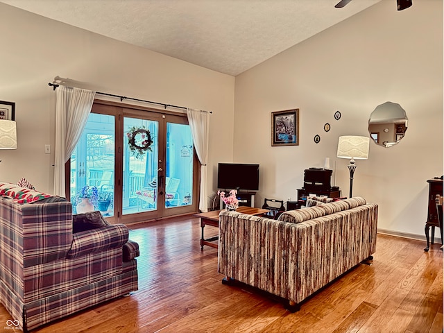 living room featuring french doors, lofted ceiling, hardwood / wood-style floors, and a textured ceiling