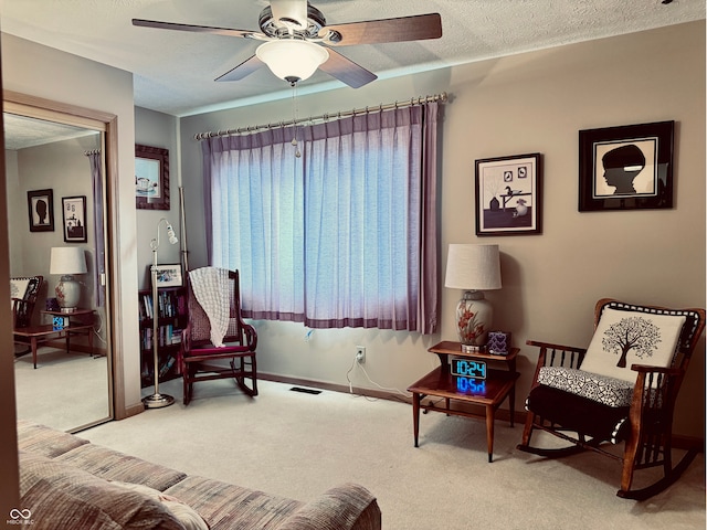 sitting room featuring ceiling fan, light colored carpet, and a textured ceiling