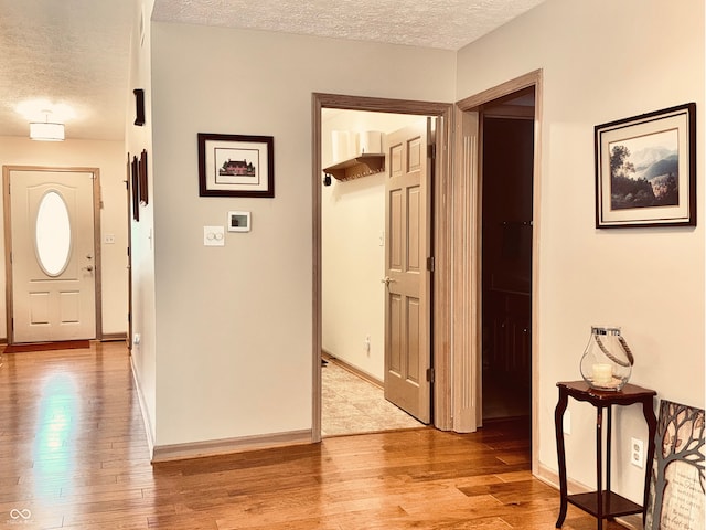 foyer entrance with light wood-type flooring and a textured ceiling