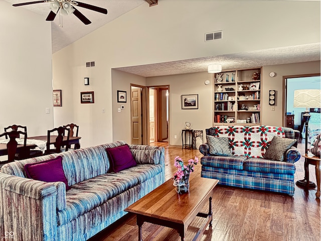 living room with wood-type flooring, high vaulted ceiling, ceiling fan, and a textured ceiling