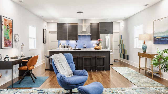 kitchen featuring stainless steel refrigerator, decorative light fixtures, tasteful backsplash, dark brown cabinetry, and wall chimney exhaust hood