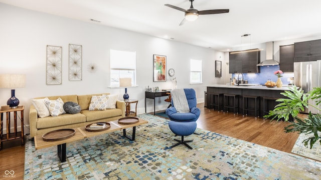 living room featuring ceiling fan, sink, and light hardwood / wood-style flooring