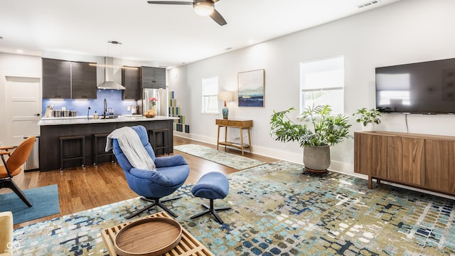 living room featuring sink, hardwood / wood-style floors, and ceiling fan