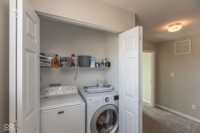 washroom with visible vents, carpet, baseboards, laundry area, and washing machine and clothes dryer