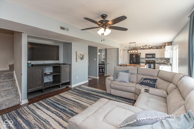 living area featuring visible vents, stairs, baseboards, ceiling fan, and dark wood-style flooring