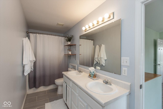 bathroom featuring double vanity, curtained shower, toilet, and a sink