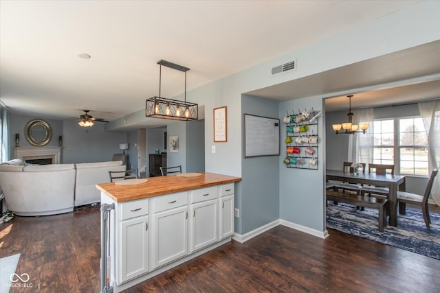 kitchen with visible vents, a fireplace, dark wood-style flooring, butcher block countertops, and white cabinets