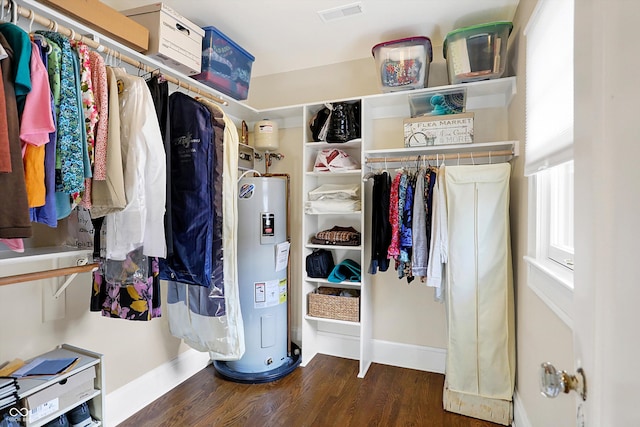 walk in closet with water heater, visible vents, and wood finished floors