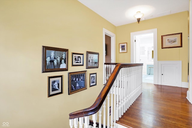 corridor with an upstairs landing and wood finished floors