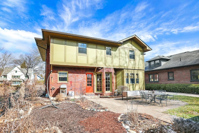 rear view of house with entry steps, a patio, and brick siding