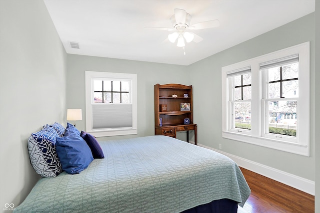 bedroom with multiple windows, visible vents, baseboards, and wood finished floors