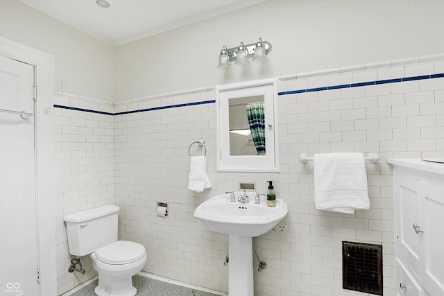 bathroom featuring toilet, tile patterned flooring, and tile walls