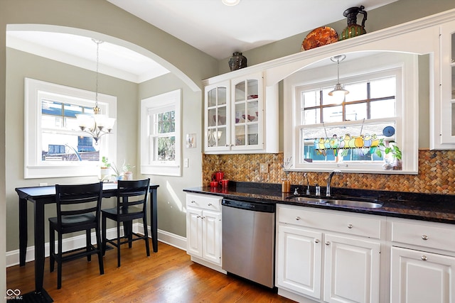 kitchen featuring a sink, white cabinets, stainless steel dishwasher, decorative backsplash, and glass insert cabinets