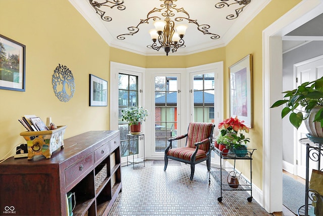 living area with ornamental molding, an inviting chandelier, and baseboards