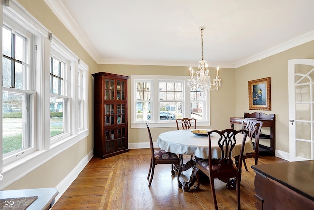 dining space featuring ornamental molding, a notable chandelier, baseboards, and wood finished floors