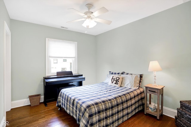 bedroom with a ceiling fan, visible vents, baseboards, and wood finished floors