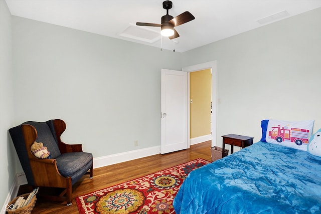 bedroom featuring attic access, visible vents, baseboards, ceiling fan, and wood finished floors